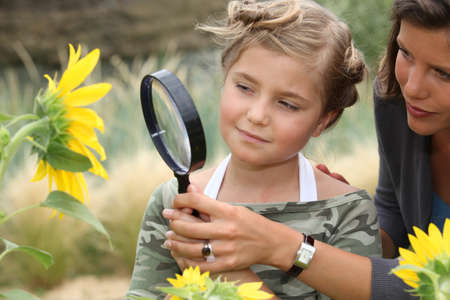 Mother and daughter looking at a sunflower with a magnifying glassの写真素材