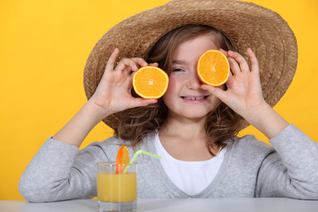 Young girl playing with oranges and drinking orange juiceの写真素材