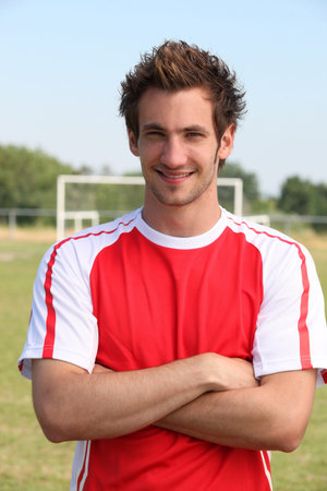 Grinning footballer with goal in the background