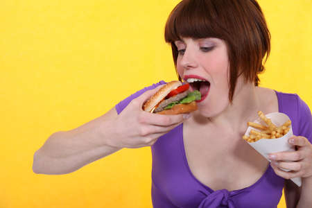 Woman eating hamburger and friesの写真素材