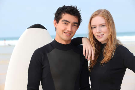 Young surfing couple in wetsuitsの写真素材