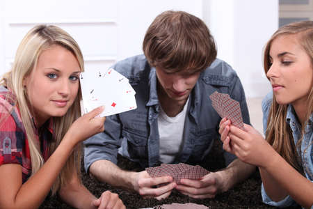 Three teenagers playing cards.の写真素材