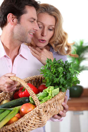 Husband showing wife vegetable basket.の写真素材