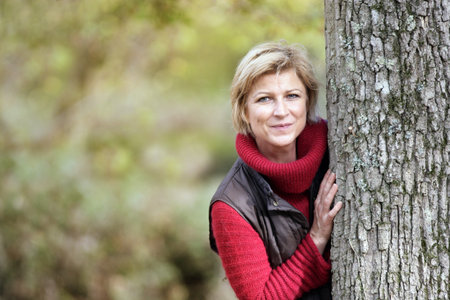 Timid woman hiding behind a tree