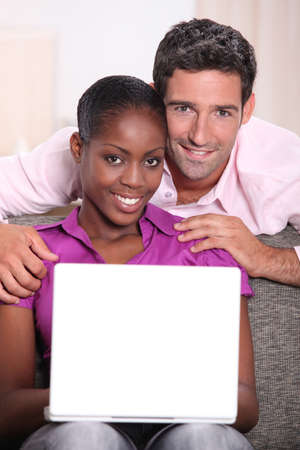 Interracial couple with a laptop.の写真素材
