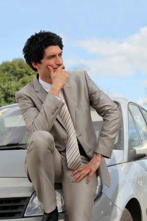 Businessman thinking by his carの写真素材