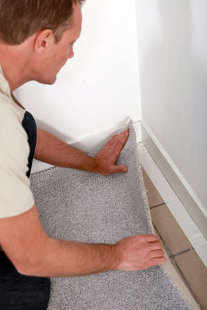 Man laying carpet into the corner of a roomの写真素材
