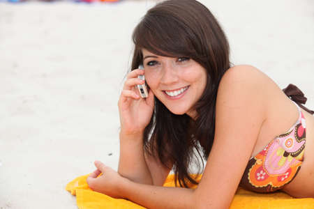 Girl on her cellphone on the beachの写真素材