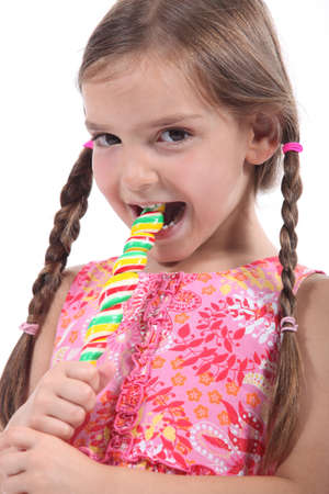 little girl with plaits sucking lollipopの写真素材