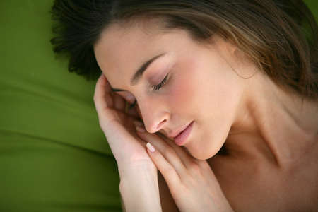 Woman asleep on a green pillowの写真素材