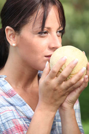 Young woman smelling a melonの写真素材