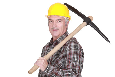 Mature laborer carrying a pickaxe on his shoulder