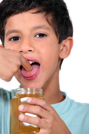Boy tasting some honeyの写真素材