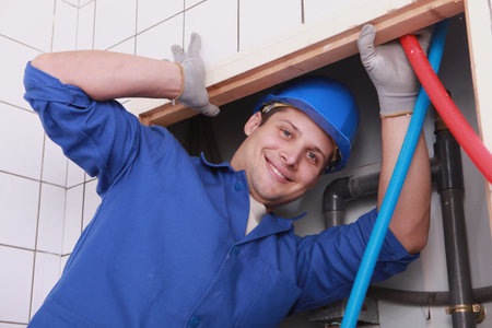 Man fixing plumbing in bathroom