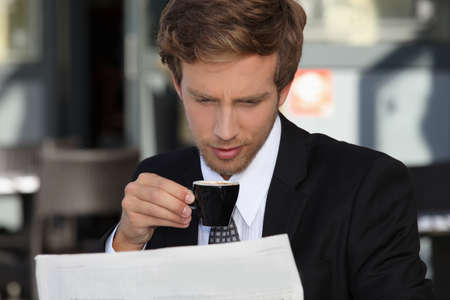 Businessman reading documents and drinking expressoの写真素材