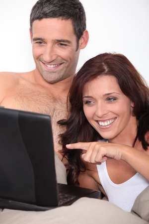 a couple laughing behind a computerの写真素材
