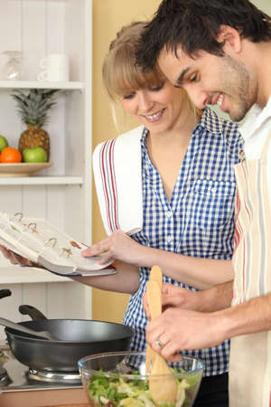 Woman and man smiling cooking using cookbookの写真素材
