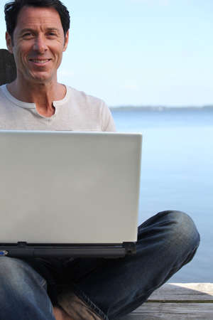 Man using a laptop computer on the waterfrontの写真素材