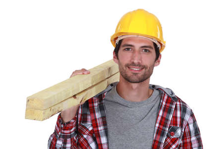 Carpenter carrying planks of wood over shoulderの写真素材