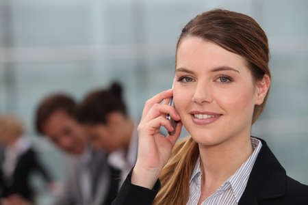 A young woman phoning in an office and looking at us.の写真素材