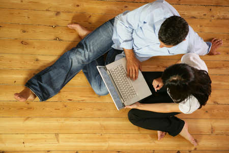 Couple in living-room with laptop computer, top-viewの写真素材