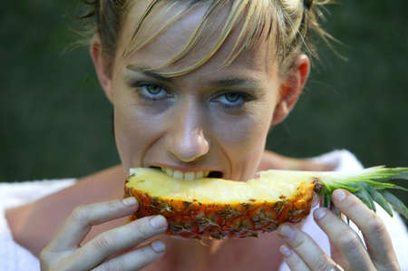 Woman eating a slice of pineappleの写真素材