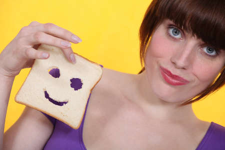 Woman with a smiley piece of breadの写真素材