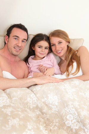 Couple in bed with their daughter