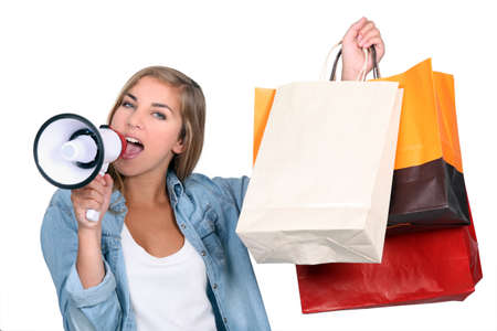 Woman holding shopping bags and shouting into a loudspeakerの写真素材