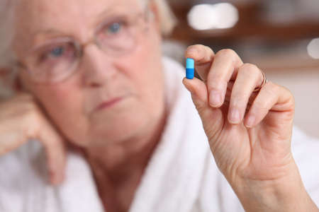 An old woman taking a pill.の写真素材