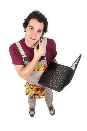Laborer in dungarees with mobile phone and computerの写真素材