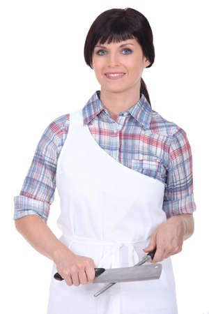 Female chef stood with knife and sharpenerの写真素材