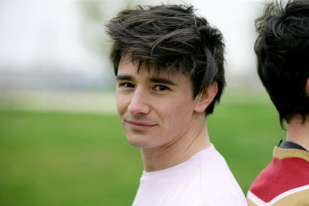 Two young men stood back to back in field