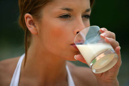 Brunette drinking glass of milkの写真素材