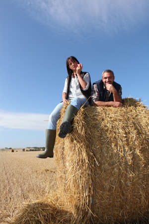 Couple sitting on bail of hayの写真素材
