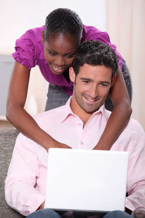 black woman leaning on his boyfriend  and doing computer laid on his boyfriendの写真素材