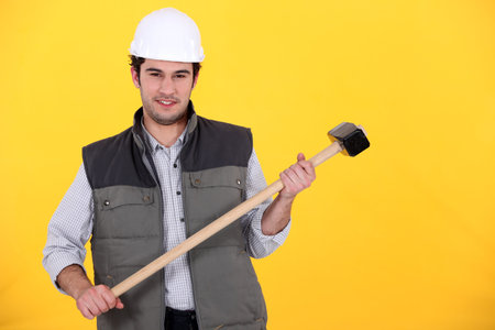 craftsman with hammer against yellow background
