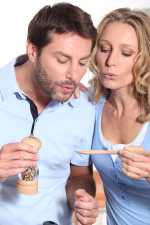 a couple cooking and watching a wooden spoonの写真素材