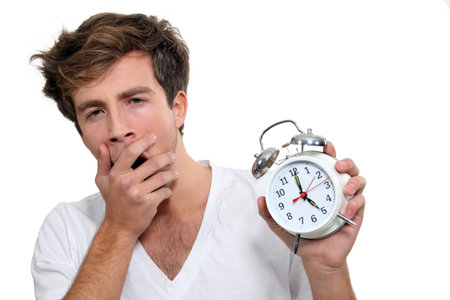 Yawning man holding alarm clock