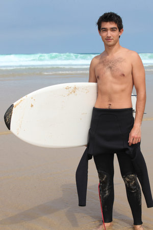 Teenage boy at the beach holding surfboard