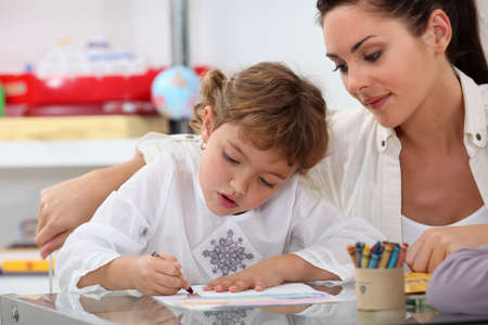 Teacher watching her pupil colouring a drawing Teacher watching her pupil colouring a drawing
