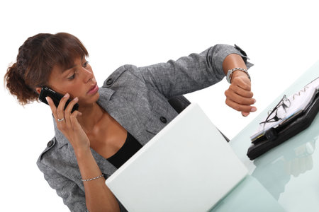 businesswoman talking on her cell and looking at her watchの写真素材