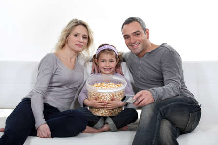 Family sitting on couch eating popcornの写真素材