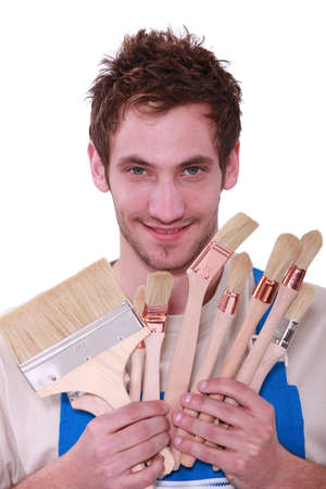 Young man with a selection of decorating paint brushesの写真素材