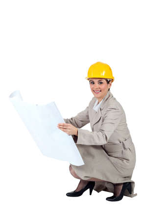 Female architect kneeling with blueprintsの写真素材