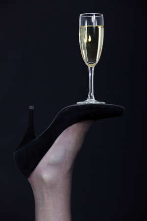 A champagne glass balanced on the sole of a shoeの写真素材