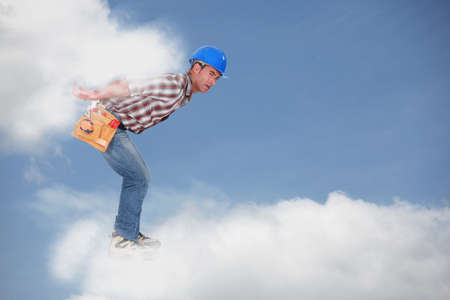 Photomontage of a young workman walking on the cloudsの写真素材