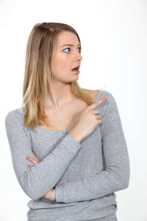 Astonished woman looking and pointing her finger sidewaysの写真素材
