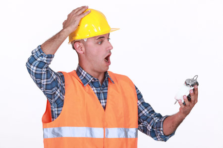 Shocked builder looking at alarm clock
