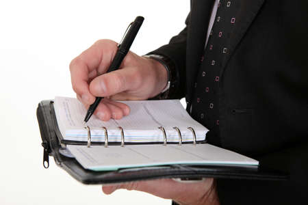 businessman noting down appointment on agendaの写真素材